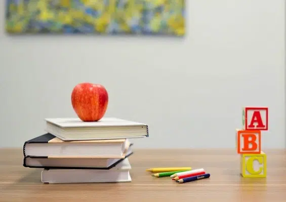 Skrivbord med böcker, pennor och ett äpple.