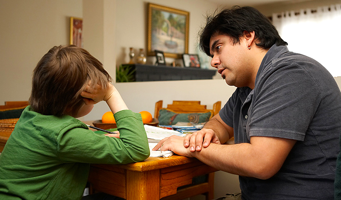 Bilden föreställer pappa som hjälper sitt barn med läxor.