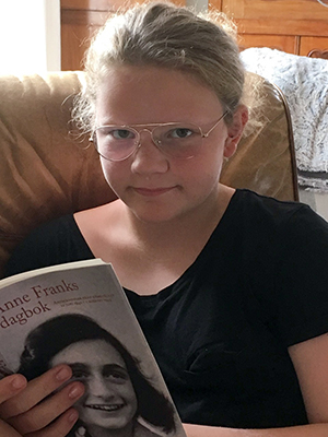 Bild på Hanna Malm, en blond tjej med glasögon som sitter och läser.