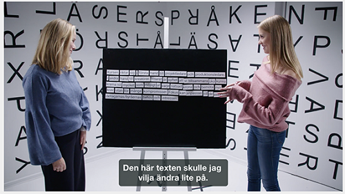 Bild på två kvinnor som samtalar framför en tavla fylld med text.