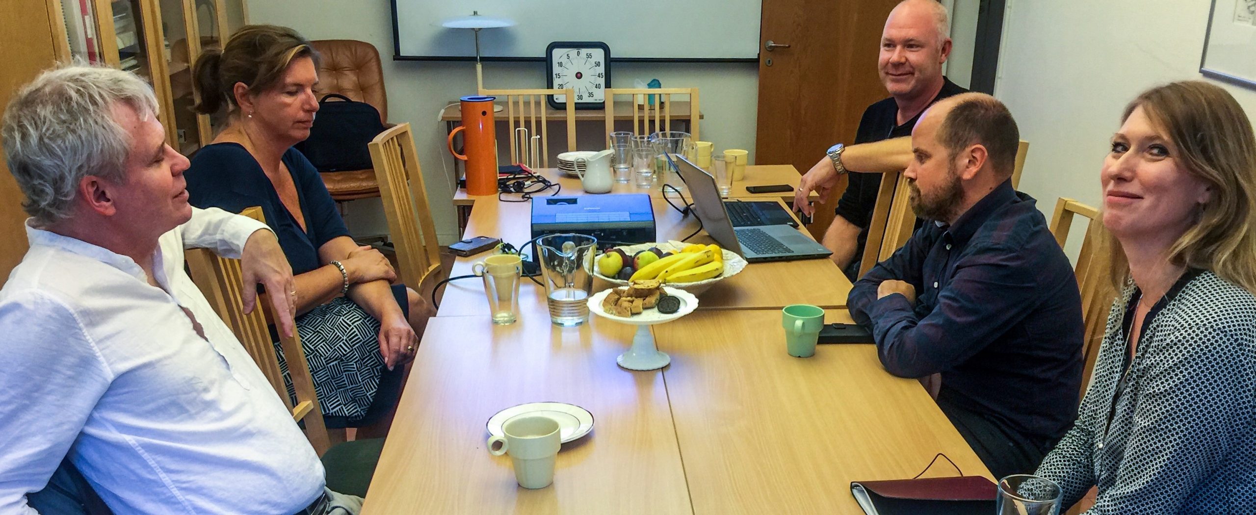 Bild från möte på Afasiförbundet, fem personer sitter inomhus runt ett bord.