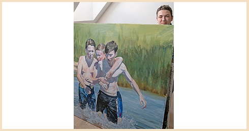 Ung man bakom en tavla som föreställer tre pojkar som leker i vattnet.