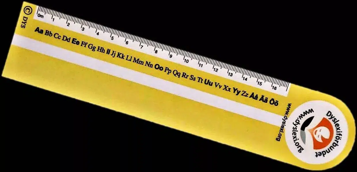 Gul linjal med bokstäver, mått och Dyslexiförbundets logotyp på.