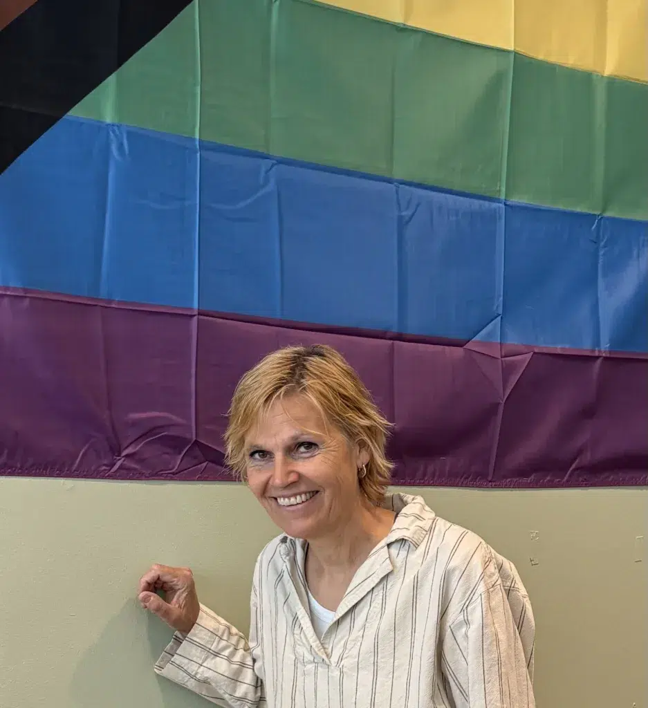 Elisabet Niskakari med blont kort hår framför ett randigt tyg i olika färger.