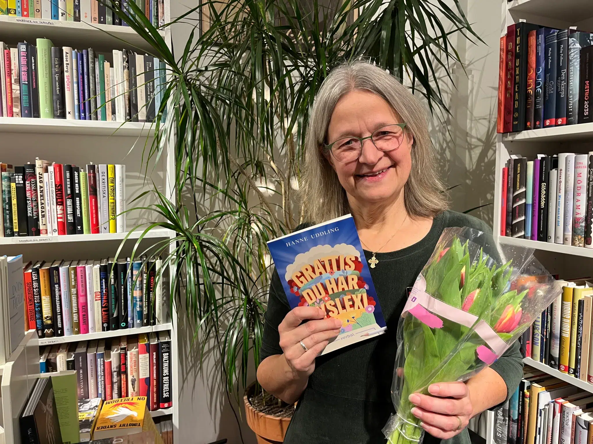 En kvinna, Hanne Uddling, håller upp sin bok "Grattis, du har dyslexi!"